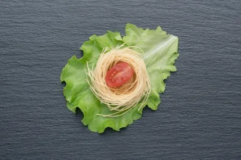 Pasta on the table, decorated with cherry tomatoes. Pasta on a dark background. Stock Photos