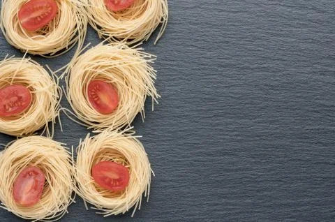 Pasta on the table, decorated with cherry tomatoes. Pasta on a dark background. Stock Photos