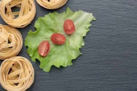 Pasta on the table, decorated with cherry tomatoes. Pasta on a dark background. Foto stock