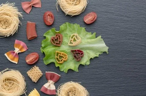 Pasta on the table, decorated with cherry tomatoes. Pasta of different shapes. Stock Photos