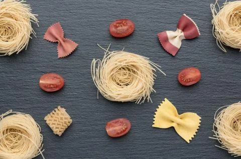 Pasta on the table, decorated with cherry tomatoes. Pasta of different shapes. Stock Photos