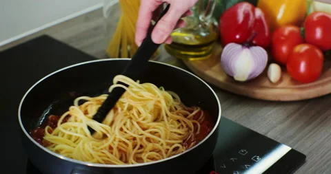 Pasta in tomato sauce in the process of cooking on the stove. A woman hand stirs Stock Footage 171939099