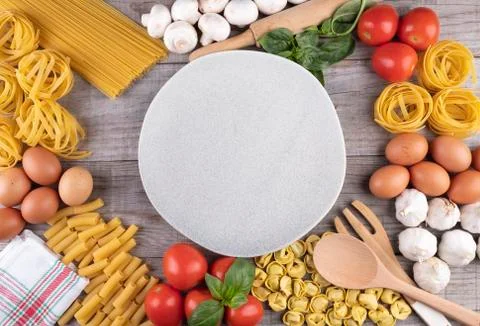Pasta, vegetables, eggs, with dish in the middle on wooden board Stock Photos