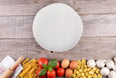 Pasta, vegetables, eggs, with dish in the middle on wooden board Stock Photos