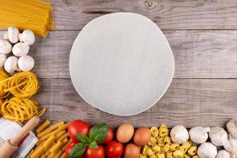 Pasta, vegetables, eggs, with dish in the middle on wooden board Stock Photos
