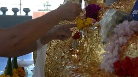Paste gold leaf petals to buddha statue at   temple Stock Footage 85415591