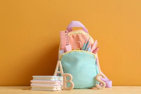 Pastel colored backpack filled with school supplies and Wooden ABC letters on 스톡 사진