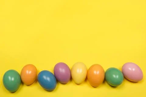 Pastel colored easter eggs on a yellow background with copy space Stock Photos