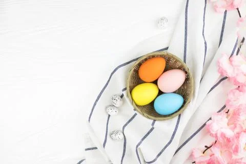 Pastel colored eggs in the nest on white wooden background. Stock Photos