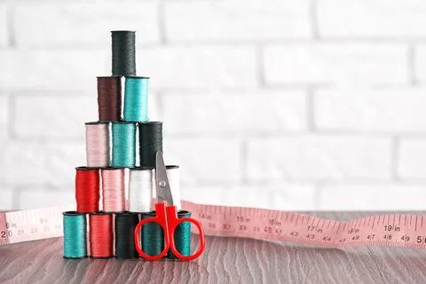 Pastel colored tailor threads stacked in pyramid form with scissors and tape Stock Photos
