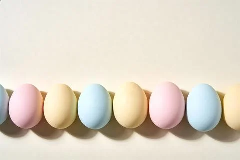 Pastel Easter eggs arranged in a row with soft shadows on a light background Stock Photos