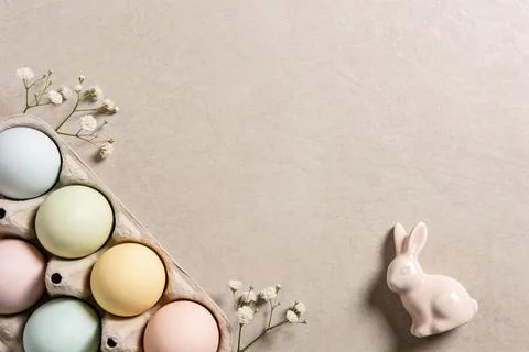 Pastel Easter eggs in a carton with delicate white flowers and a pink bunny.. Stock Photos