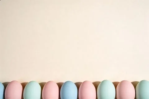 Pastel Easter eggs in a row casting shadows on a light background, top view Stock Photos