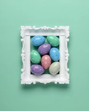 Pastel Easter eggs sit inside ornate white frame on mint background, calm s.. 写真素材