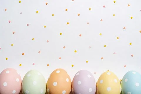 Pastel Easter eggs with white polka dots arranged in a row on a dotted back.. Stock Photos