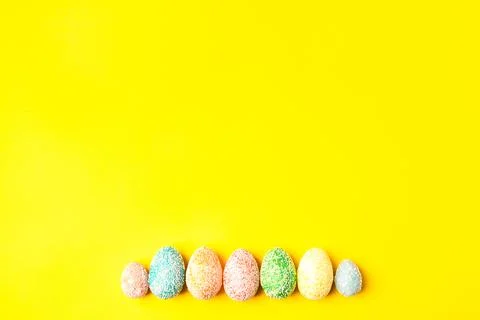 Pastel eggs on yellow background down side with space for text. Happy easter. Stock Photos