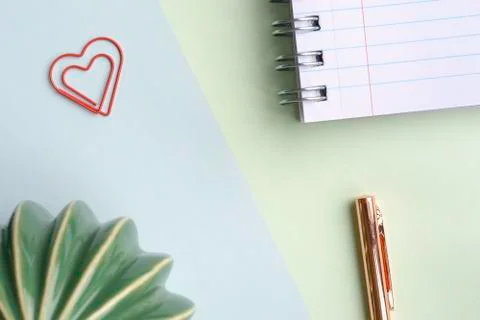 Pastel green blue background with a notebook, pen, heart paper clip and cactu Stock Photos