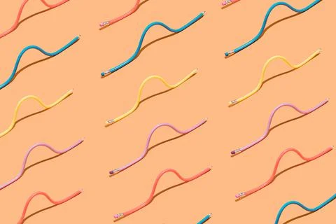 Pastel multi colored pencils in pattern on brown background. 스톡 사진