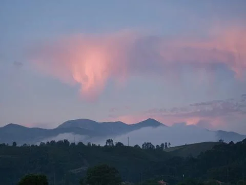 Pastel Pink Clouds Over Misty Mountain Range - Pastel colored pink and purp.. Stock-Fotos