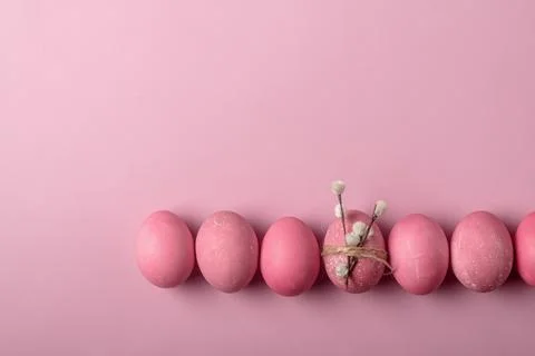 Pastel pink Easter eggs form border on wide background, decorated egg with .. Stock Photos