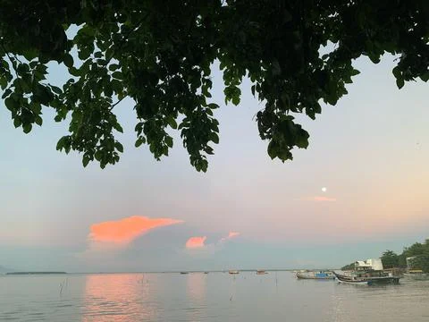 Pastel Sunset Clouds and Moon Above Calm Sea at Tanjung Lesung Beach Stock Photos