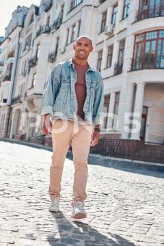Pastime. Young guy walking on city street smiling cheerful Stock Photos