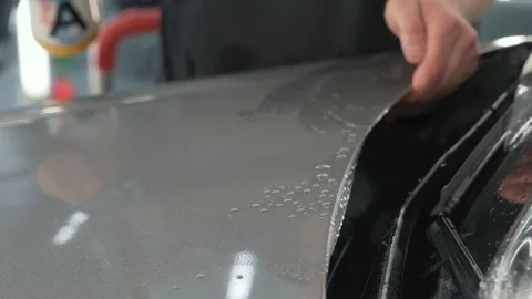 Pasting or installing car hood with protective polymer film or PPF, worker hands Stock Footage 149945628