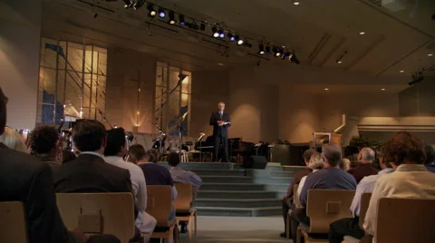 Pastor closing sermon, congregation rising, zoom-in to praying pastor Stock Footage