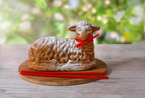Pastries in the form of an Easter lamb with red candles on the table in the.. Stock Photos