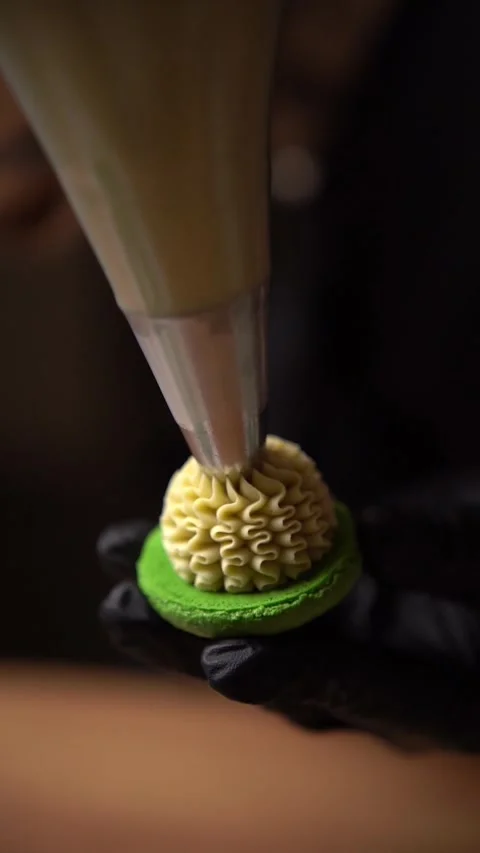 The pastry chef adds cream using a cooking bag to the finished green macaron hal Video stock 294720705