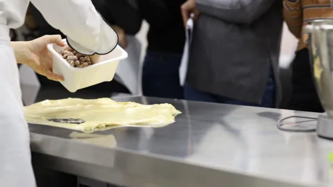 A pastry chef adds a mix of nuts and dried fruits to a panettone dough Stock Footage 121036475