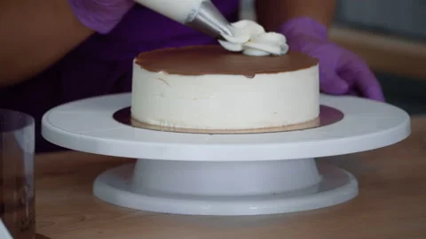 Pastry chef applies a creamy pattern to a cake. Stock Footage 167825710