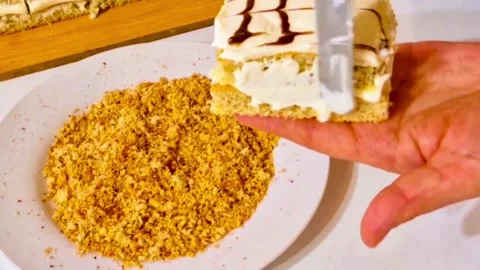Pastry chef applying crushed nut crumbs to the side of a cream cake slice Stock Footage 327258965
