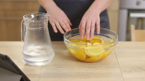 A pastry chef in apron cools sliced ​​oranges in a bright kitchen Stock Footage 231238146