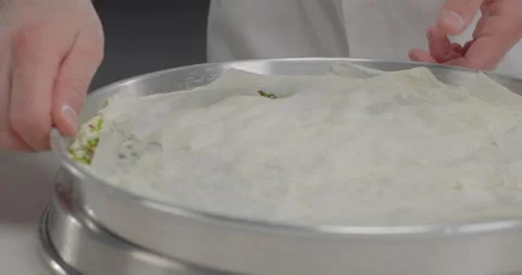 Pastry chef arrange phyllo dough sheets on pistachios in a tray. Turkish dessert Stock Footage 285784337