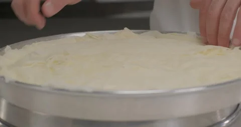 Pastry chef arrange phyllo dough sheets on a round tray. Turkish dessert baklava Stock Footage 293841242