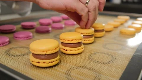 The pastry chef assembles macarons with chocolate cream. Stock Footage 148659965