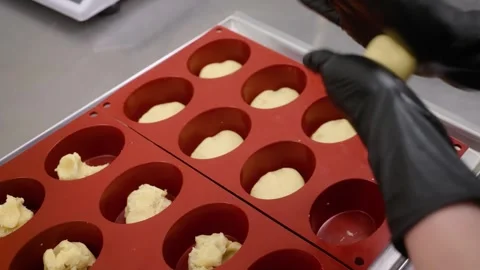 Pastry Chef in Black Gloves Placing Dough into Red Silicone Molds for Gourmet Mi Stock Footage 337751565