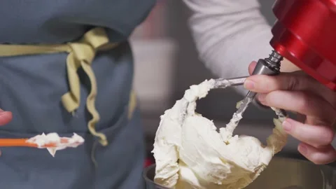 The pastry chef cleans the blades of the planetary mixer from the white cream Stock Footage 147577880