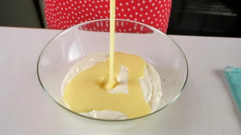 Pastry chef combining condensed milk with sour cream in glass bowl. Stock Footage 311534683