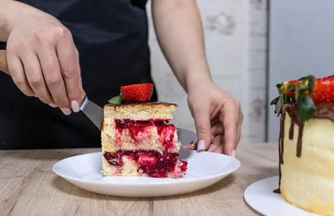 The pastry chef cuts a sponge cake with cheese cream and strawberries Stock Photos