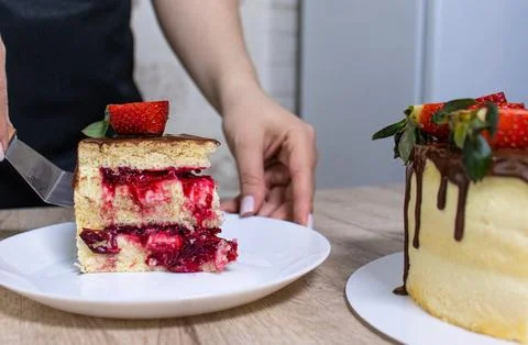 The pastry chef cuts a sponge cake with cheese cream and strawberries Stock Photos