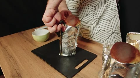 Pastry chef cuts through a foil pan to reveal a freshly baked loaf of bread Video stock 330537101