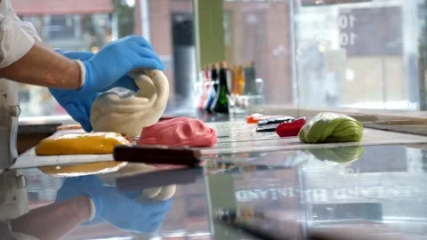 A pastry chef cutting off caramel with scissors on a table in a pastry shop. Stock Footage 330522147