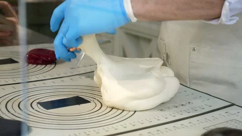 A pastry chef cutting off caramel with scissors on a table in a pastry shop. Stock Footage 330870104