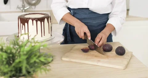 The pastry chef is cutting figs and decorating a cake or cheesecake. Close-up. Stock-Footage 167812054