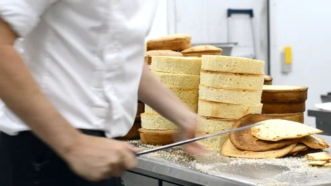Pastry chef cutting the sponge cake on layers. Cake production process. Stock Footage 102261666