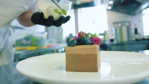 Pastry chef decorates a cake with berries and mint Stock Footage 112948372