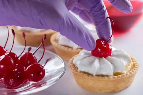 Pastry chef decorates cake with cherry. 写真素材