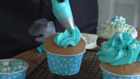 The pastry chef decorates the cupcake with blue cream. Stock Footage 155401515